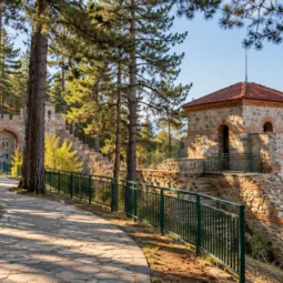 Каменна алея с пейки сред борови дървета край крепостна кула на Хисарлъка