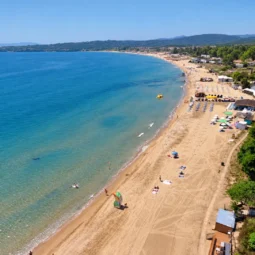 Панорамна гледка към пясъчен плаж, синьо море и зелен крайбрежен район